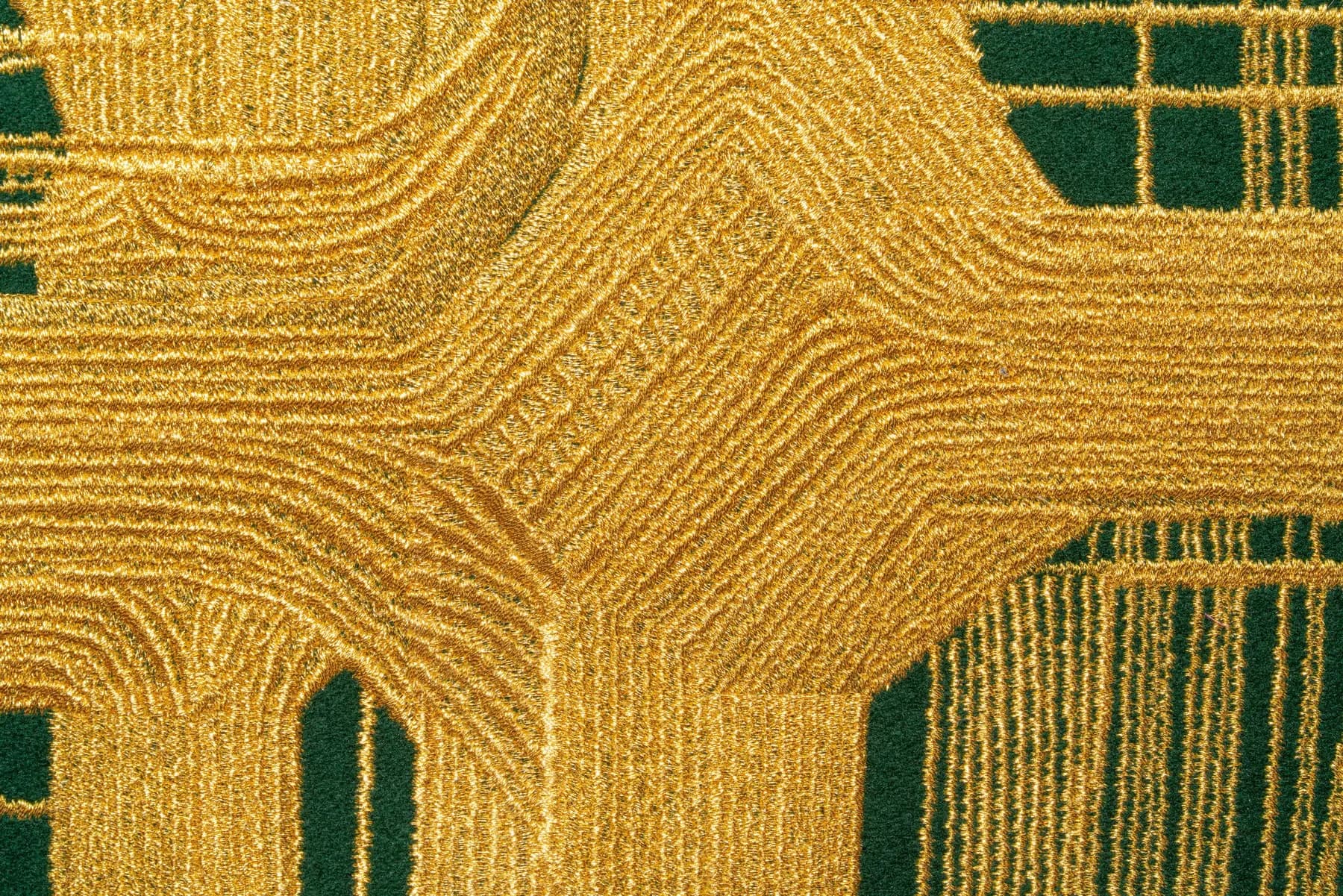 Aurum Aura (detail) — close-up of raised golden threads and curved stitch patterns against green cashmere