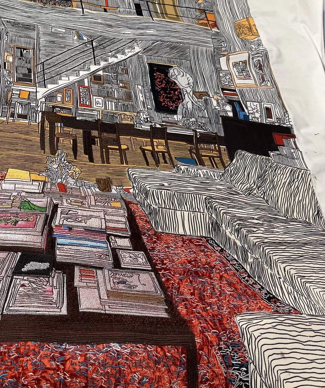 The Rooms We Carry (detail) — close-up of embroidered books, carpets and furnishings, revealing the layered stitch textures